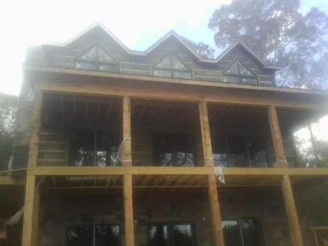 Dormers and porch framing on a large log home under construction — Roof Coating work by our crew in Cottonwood