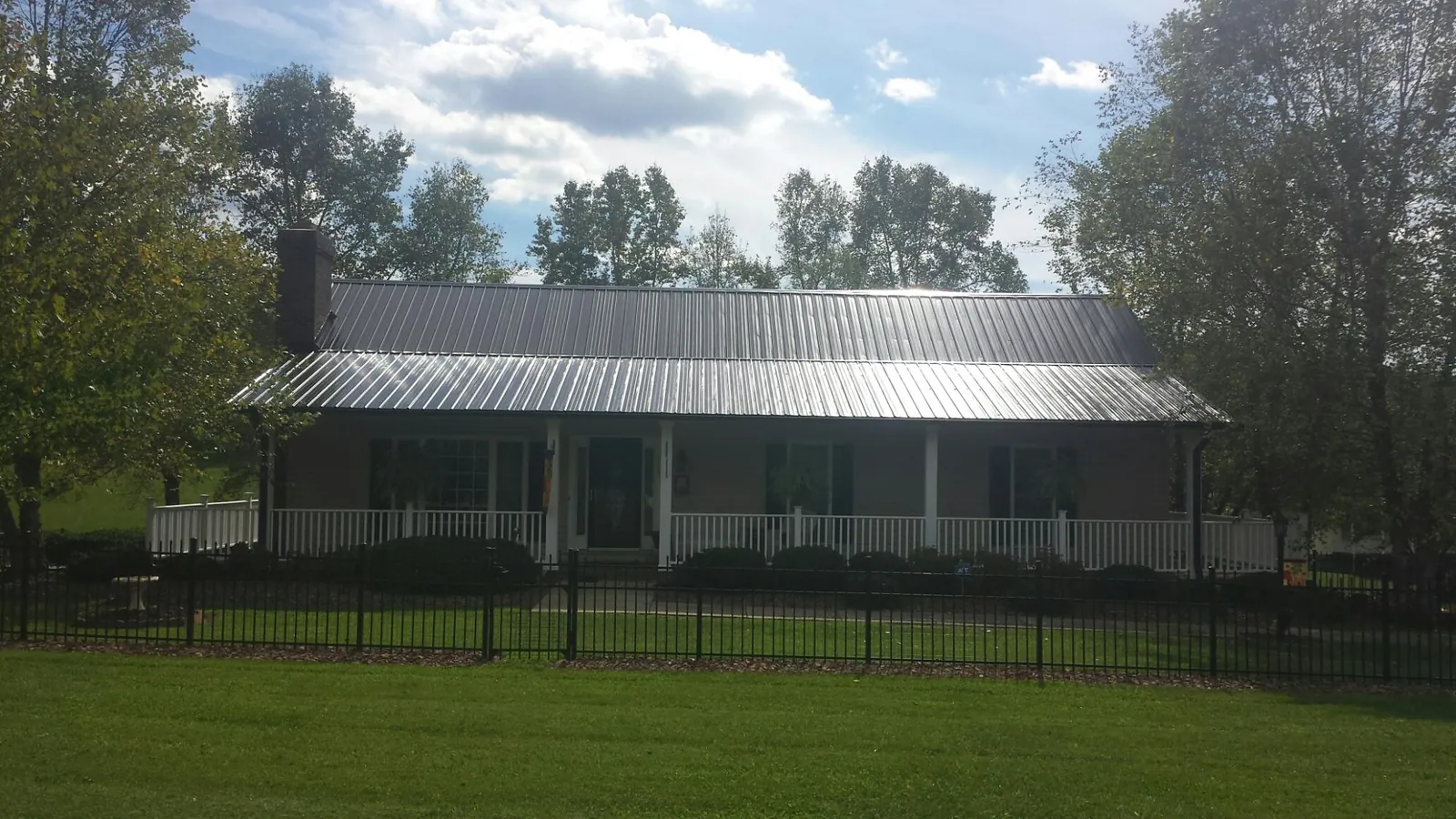 Gray metal roof on a brick ranch with a full width front porch — Gutter Guard Installation work by our crew in Cottonwood